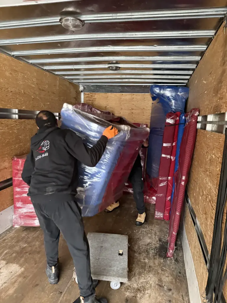 Deux déménageurs installent un meuble protégé dans le camion