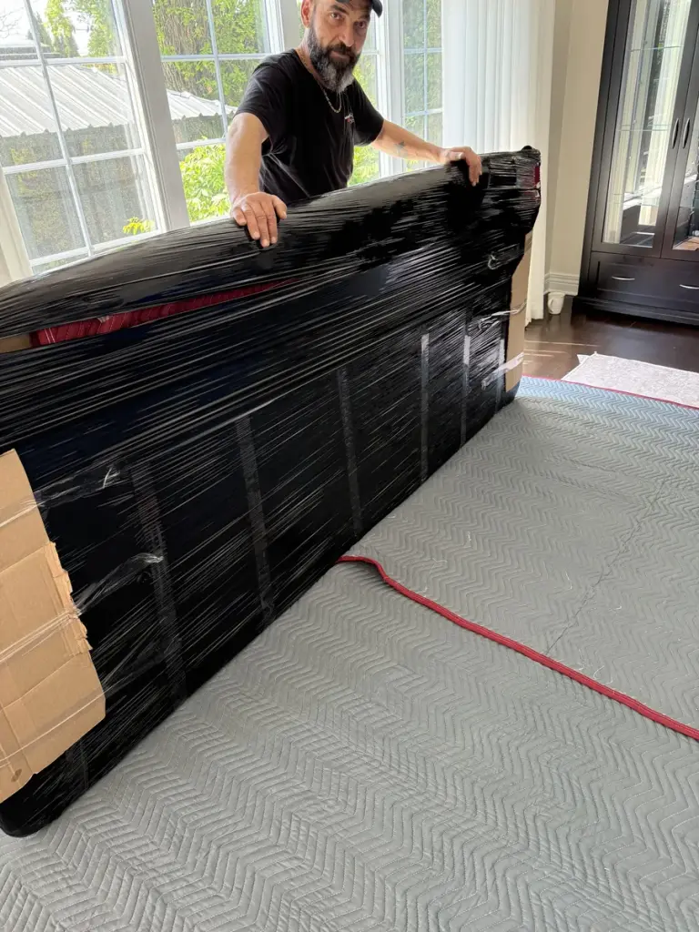 Un déménageur emballe un élément de mobilier sur un plancher protégé