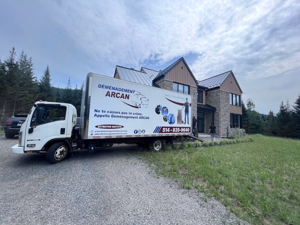 Camion Déménagement Arcan devant une maison entourée d’arbres à Laval