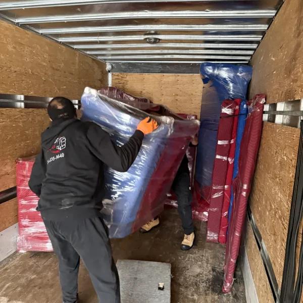 Deux déménageurs installent un meuble protégé dans le camion