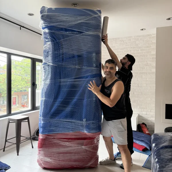 Deux membres de l’équipe protègent un grand meuble