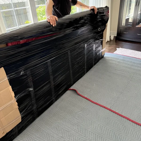 Un déménageur emballe un élément de mobilier sur un plancher protégé